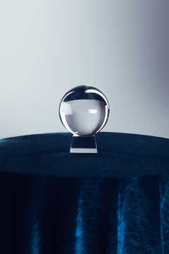 Crystal ball on round table with dark blue tablecloth on grey background