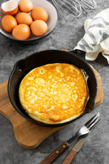 Traditional omelette on black frying pan in black, skillet black pan, dark food photo.