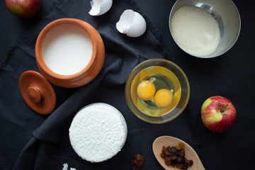 Obraz na płótnie Canvas Ingredients for the recipe: cottage cheese, raw eggs, apple, sour cream, raisins