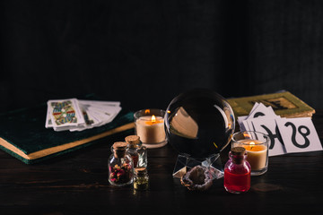 KYIV, UKRAINE - JANUARY 9, 2020: selective focus of tarot cards and crystal ball with occult objects on wooden and black background