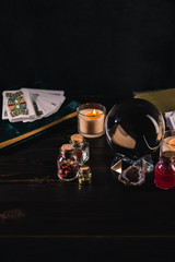 KYIV, UKRAINE - JANUARY 9, 2020: tarot cards and crystal ball with occult objects on wooden and black background