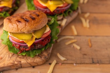 Burgers on a wooden background with french fries, with space for design