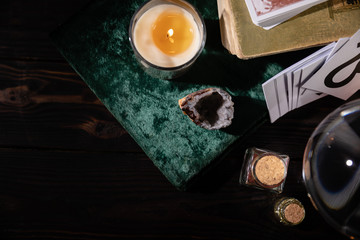 KYIV, UKRAINE - JANUARY 9, 2020: top view of candle, books and occult objects on wooden background