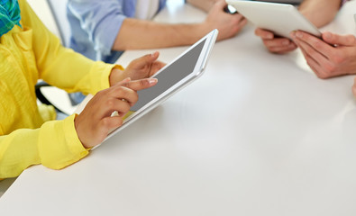 education, technology and people concept - group of international high school students or classmates with tablet pc computers at table