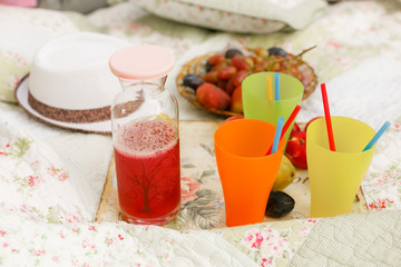 Picnic on nature, on a bedspread fruit, drinks and white hat