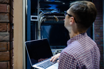 In the server room a technician/ It engineer/ hold the notebook