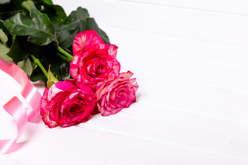 Roses and red ribbon on white background. The concept of the holidays