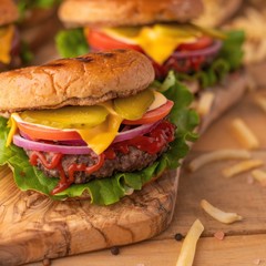 Burgers on a wooden background with french fries, with space for design
