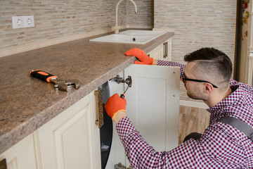 worker in uniform repair a wood closet door