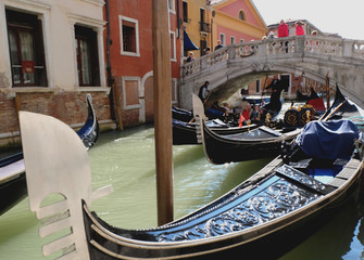 Fototapeta na wymiar Venetian gondolier punting gondola through canal waters of Venice Italy