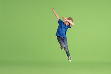 Dabbing. Happy boy playing and having fun on green studio background. Caucasian kid in bright cloth...