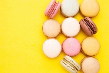 Abstract beauty summer or spring background with colorful macaroons cookies, over yellow background with copy space. Traditional french dessert.