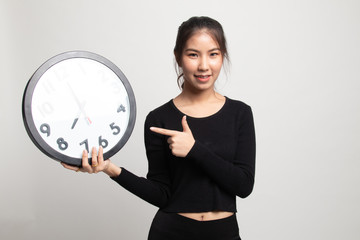 Young Asian woman point to a clock.
