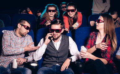 The guy speaks on the phone and interferes with watching a movie in a movie theater. Stock photo of...
