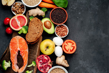 Selection of healthy food: salmon, fruits, seeds, cereals, superfoods, vegetables, leafy vegetables on a stone background   with copy space for your text.Healthy food for people 