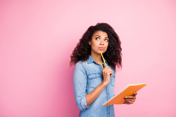 Portrait of minded afro american brunette wavy hair girl hold copy book want write report think thoughts wear casual style clothing isolated over pink color background