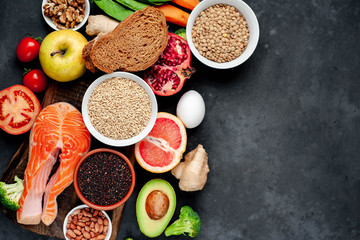 Selection of healthy food: salmon, fruits, seeds, cereals, superfoods, vegetables, leafy vegetables on a stone background   with copy space for your text.Healthy food for people 