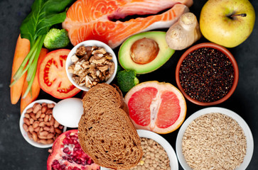 Fototapeta na wymiar Selection of healthy food: salmon, fruits, seeds, cereals, superfoods, vegetables, leafy vegetables, eggs, rye bread on a stone background