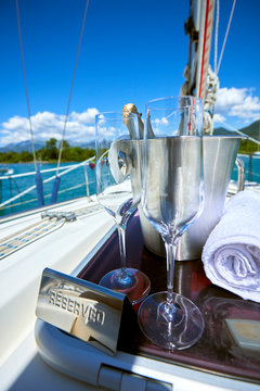 Romantic luxury evening on cruise yacht with champagne setting. Empty glasses and bottle with champagne and tropical sunset with sea background