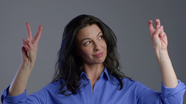 Pretty woman showing with hands and two fingers like quotes gesture, bend fingers isolated over grey background. Very funny, irony and sarcasm concept.