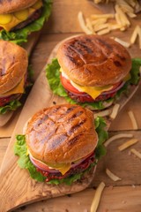 burgers, fast food. Calorie and tasty food. On a wooden background, vertical photo