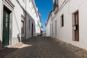 Fototapeta premium Narrow street with traditional white houses of an old town in the south of Portugal