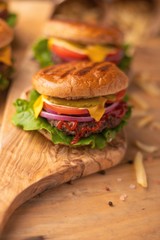 Hamburgers and burgers with french fries on a wooden texture, vertical frame