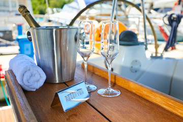 Romantic luxury evening on cruise yacht with champagne setting. Empty glasses and bottle with champagne and tropical sunset with sea background