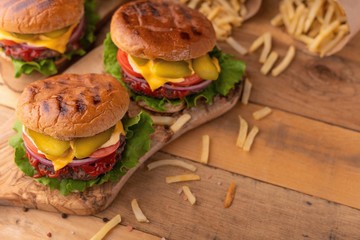 Juicy homemade french fries burgers. Wooden texture with space for design. Delicious and fast food.