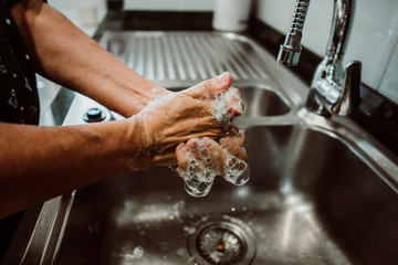 Middle-aged woman washing her hands with soap and water to avoid contagion of the coronavirus. Health risk prevention in old population. Healthcare