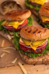Hamburgers and burgers with french fries on a wooden texture, vertical frame