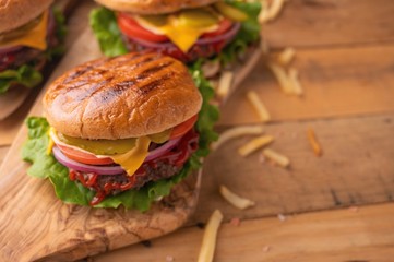 Juicy homemade french fries burgers. Wooden texture with space for design. Delicious and fast food.
