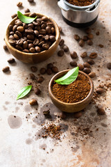 Ingredients for a coffee machine. Coffee beans and ground powder on a stone countertop. Copy space.
