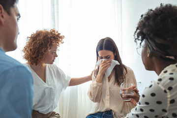Upset woman in trouble get psychological support during therapy session, diverse friends people comforting helping depressed woman having trauma problem addiction at psychotherapy counseling