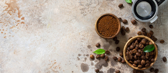 Ingredients for a coffee machine. Coffee beans and ground powder on a stone countertop. Top view flat lay background. Banner.