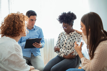 Comforting of addict. People counseling desperate woman at group therapy session. Distraught woman during counseling session. Woman getting psychological support during therapy session
