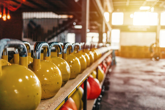 Kettlebells with various colors. Sport equipment in gym. kettlebell on floor background, Fitness training. Shot of a bunch of kettle bells lined up in a row on the floor of a gym