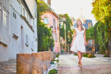 Woman in white dress walking on famous Montmartre hill in Paris, France at early morning