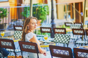 Woman having breakfast or brunch in traditional French cafe on Montmartre in Paris, France