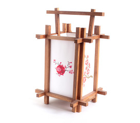 A traditional Japanese-style lamp made of wood and paper with cherry flowers stands on a white isolated background..