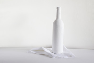 Painted white bottle on a towel on a light background.