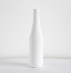 Silhouette of a white painted bottle on a gray background.