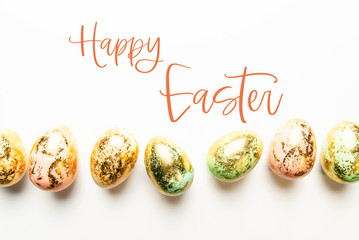 Happy Easter text. Natural Golden Speckled Easter Eggs of pastel colors on white background. Happy Easter card concept, minimalistic design, copy space