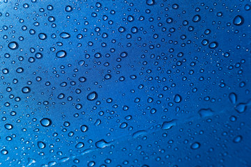 Close-up of natural and refreshing raindrops on the fabric of a colored umbrella.