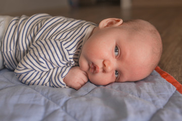 Baby boy lying on front in living room 