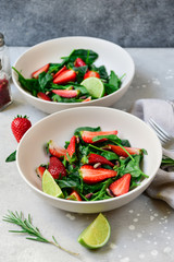 Fitness food spinach and strawberry salad in white bowls on a light table. food delivery of diet dishes. dish for spring and summer menu business lunch. the view from the top. selective focus