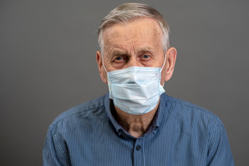 Portrait of an old man in a medical protective mask. A concept of the danger of coronavirus for the...