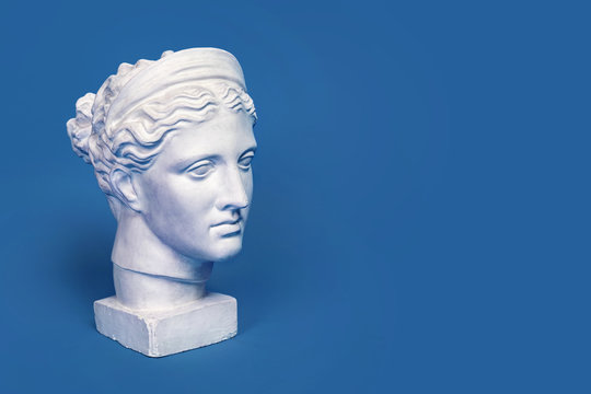 Marble head of young woman, ancient Greek goddess bust isolated on pink background. Gypsum copy of a statue Diana head
