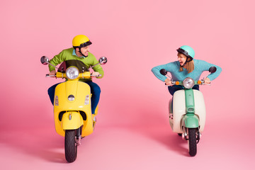 Who is first. Full length photo of crazy funny lady guy driving two vintage moped speed race competition wear casual outfit colorful protective headgear isolated pink color background