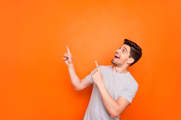 Fototapeta Photo of attractive funny crazy guy hold hands fingers direct up empty space excited good mood sales person wear striped t-shirt isolated bright orange color background obraz